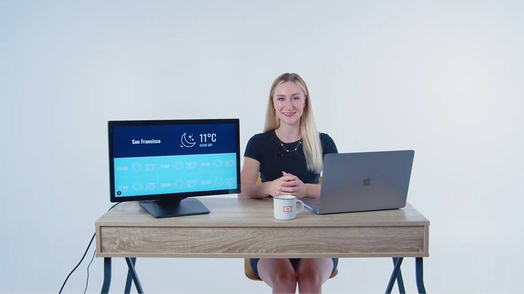 Woman presenting digital signage weather display with Yodeck branding